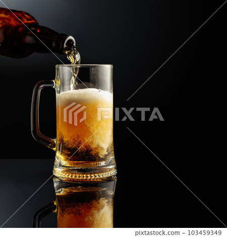 Pouring beer from a bottle into a mug. 103459349