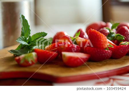 Still life. Food background with sliced ripe organic fresh strawberries and mint leaves on a wooden cutting board. Nourishment. Healthy nutrition. Slimming and dieting concept. Raw vegan. Close-up 103459424