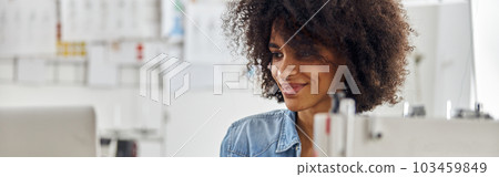African-American woman uses laptop at workplace with sewing mach 103459849