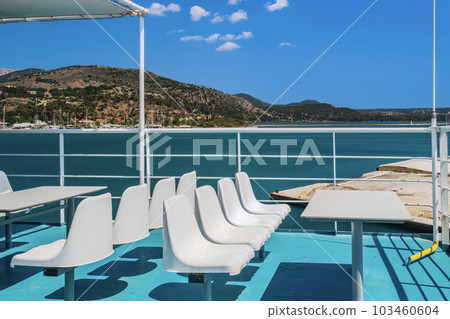 White empty plastic fiberglass chairs and seating area with tables on a ferry boat under a bright summer sky. 103460604