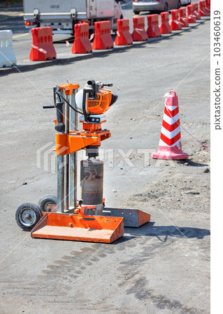 Drilling gasoline machine for cutting samples of asphalt concrete on the background of road repair. Drilling gasoline machine for cutting samples of asphalt concrete on the background of road repair. 103460619