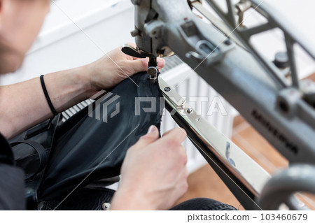 Black leather bag repair in a tailoring studio, leatherworking concept 103460679
