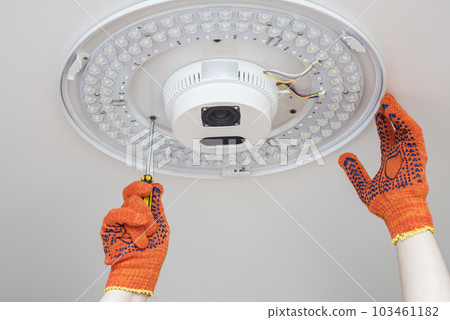 An electrician installs a chandelier on the ceiling. An electrician installs a chandelier on the ceiling. 103461182