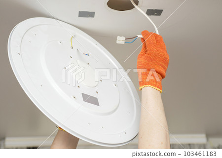 An electrician installs a chandelier on the ceiling. An electrician installs a chandelier on the ceiling. 103461183