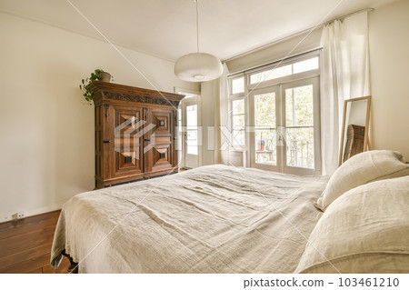 a bedroom with a bed, dresser and large window looking out onto the backyard patio area in the photo is taken 103461210
