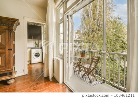 a balcony with a washing machine in the window and an open door that leads out to a small patio area 103461211