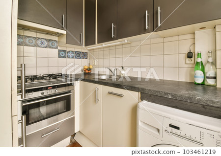 a kitchen with an oven, dishwasher and washing machine in the middle part of the room on the right side a kitchen with an oven, dishwasher and washing machine in the middle part of the room on the right side 103461219