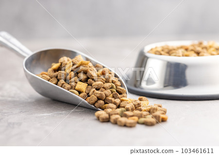 Dry kibble pet food. Dog or cat food in scoop on gray table. 103461611