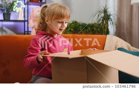 Happy child girl shopper unpacking cardboard box delivery parcel online shopping purchase at home Happy child girl shopper unpacking cardboard box delivery parcel online shopping purchase at home 103461796