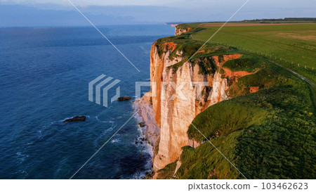 Sheer cliffs of Etretat (Normandy) at sunset rays and water of English Channel 103462623