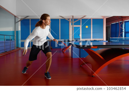 Young man table tennis player kicking ball with racket in motion Young man table tennis player kicking ball with racket in motion 103462854