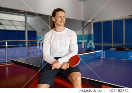 Satisfied sportsman having rest after training sitting on tennis table 103462861