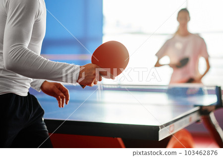 Selective focus on two sportive people playing table tennis indoors 103462876