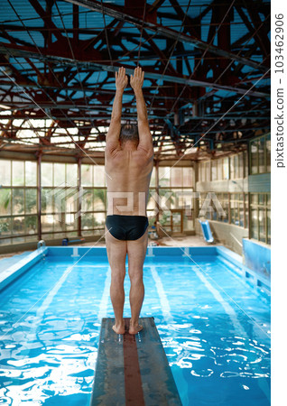 Back side view on strong senior man swimmer starting diving jump in pool 103462906