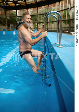 Smiling glad senior man swimming trunks getting out from pool Smiling glad senior man swimming trunks getting out from pool 103462938
