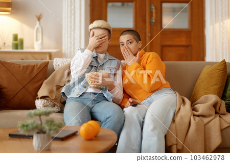 Young lesbian woman couple watching scary movie at home Young lesbian woman couple watching scary movie at home 103462978