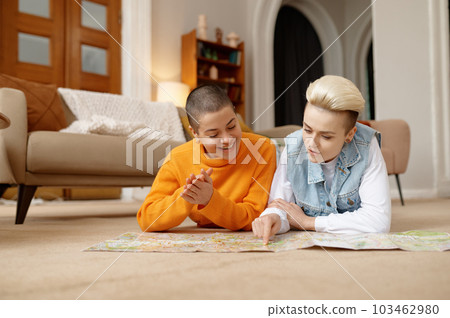 Young lgbt woman couple planning travel on weekends choosing rout on paper map 103462980