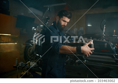 Auto mechanic working on sports bike in authentic workshop garage 103463002