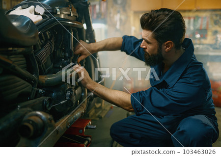 Young mechanic working on motorcycle in garage repair service Young mechanic working on motorcycle in garage repair service 103463026