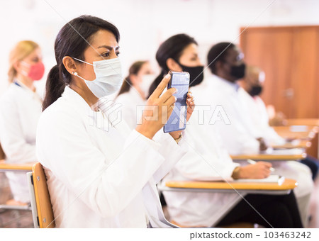 Hispanic female doctor in protective recording lecture on smartphone Hispanic female doctor in protective recording lecture on smartphone 103463242