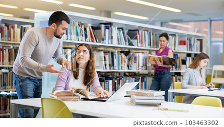 Man recommending books to woman in public library Man recommending books to woman in public library 103463302