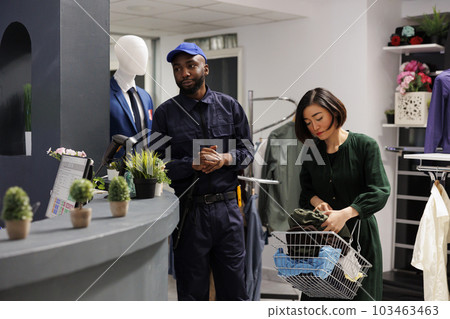 Young African American man retail security officer wearing uniform standing at clothes shop cashier counter, ensuring safety of employees and customers, patrolling clothing store Young African American man retail security officer wearing uniform standing at clothes shop cashier counter, ensuring safety of employees and customers, patrolling clothing store 103463463