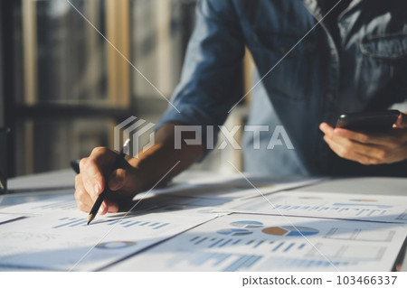 Close up of businessman is analyzing the stock marketing on smartphone. He is looking at financial and statistic. Close up of businessman is analyzing the stock marketing on smartphone. He is looking at financial and statistic. 103466337