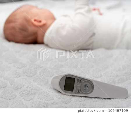 Infrared thermometer and a newborn baby in the background as a concept for a modern temperature measurement method 103467199