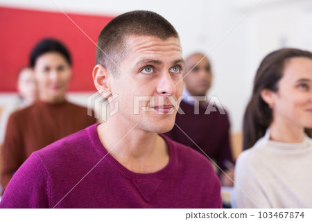 Attentive students at their desks in university auditorium 103467874