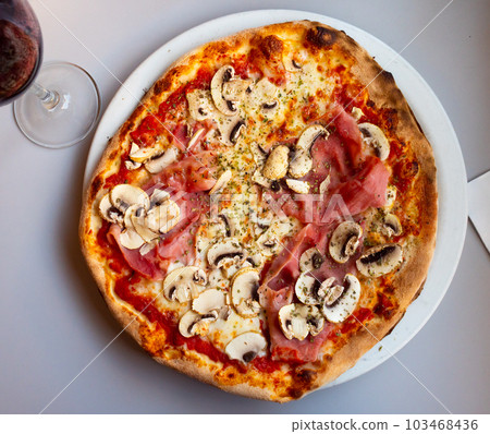 Pizza with mushrooms and ham served on a plate Pizza with mushrooms and ham served on a plate 103468436