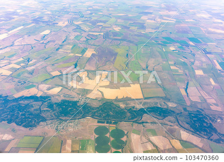 Aerial view from airplane window above green ground. View from the airplane window with beautiful clouds at sunrise 103470360