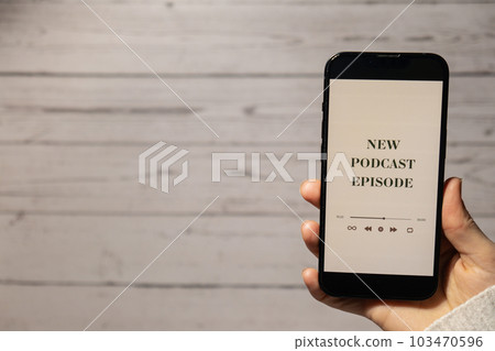 Unrecognizable woman holding mobile phone NEW PODCAST EPISODE listening website page app application with wireless headphones. Audio healing, sound therapy wellness rituals, positive mental health 103470596