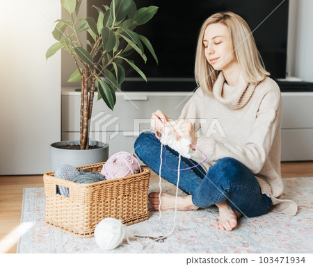 Young woman knitting warm scarf indoors Young woman knitting warm scarf indoors 103471934