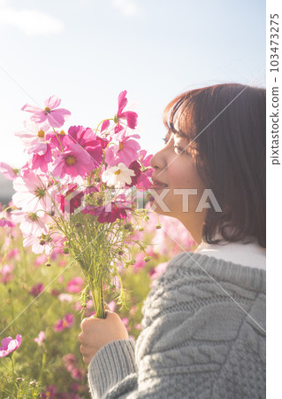 A woman standing with a bouquet in a cosmos field A woman standing with a bouquet in a cosmos field 103473275