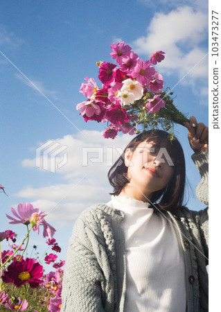 A woman standing with a bouquet in a cosmos field A woman standing with a bouquet in a cosmos field 103473277