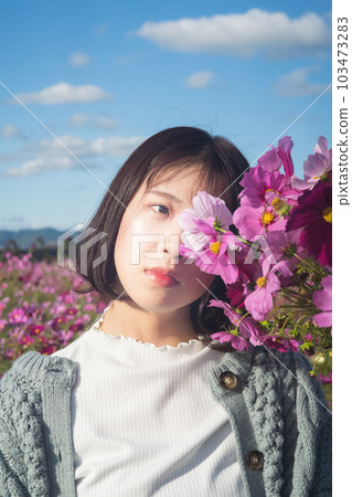 A woman standing with a bouquet in a cosmos field A woman standing with a bouquet in a cosmos field 103473283