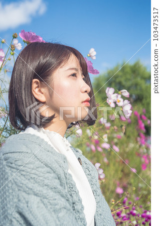 Woman sitting in cosmos field 103473517