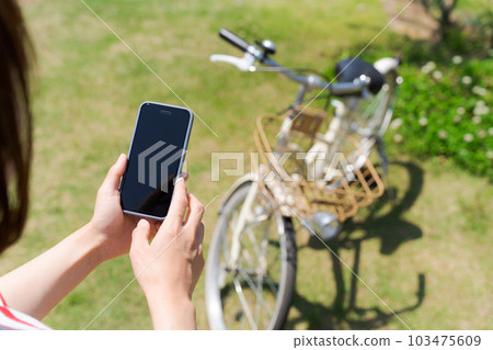 Hand photo of a woman operating a bicycle and a smartphone 103475609