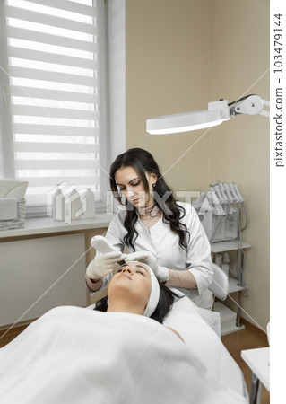 Cleansing the skin to a new level: this photo demonstrates how professional cosmetologist applies ultrasonic facial cleansing to thoroughly cleanse skin impurities and give it freshness and radiance. 103479144