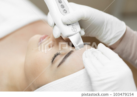 Healthy and radiant skin: thanks to ultrasonic facial cleansing from professional cosmetologist, skin becomes healthy, cleansed toxins and filled natural radiance. Woman in beauty clinic face close-up Healthy and radiant skin: thanks to ultrasonic facial cleansing from professional cosmetologist, skin becomes healthy, cleansed toxins and filled natural radiance. Woman in beauty clinic face close-up 103479154