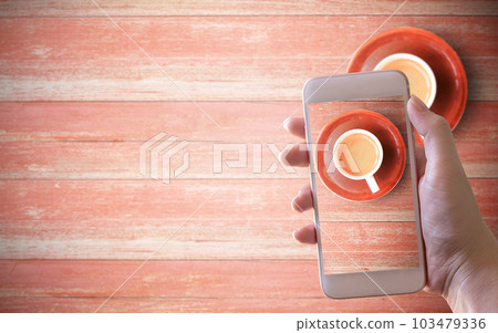 Mockup image of hand holding white mobile phone with cup of coffee 103479336