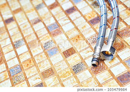 Plumbing. Flexible metal stainless steel faucet hoses on light brown pvc panel 103479984