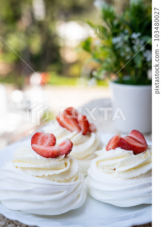 Homemade meringue dessert Pavlova cake with fresh strawberries and mint. Summer dessert. French cake. Confectionery. Classic dessert. Strawberry dessert 103480027
