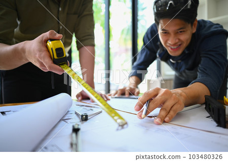 Male architect planning development details, working on construction plans with colleagues in office Male architect planning development details, working on construction plans with colleagues in office 103480326
