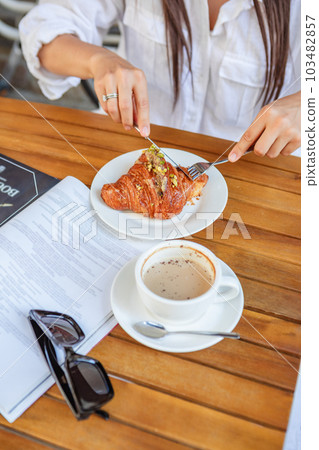 Cozy cafe moment with croissant, coffee, and magazine Cozy cafe moment with croissant, coffee, and magazine 103482857