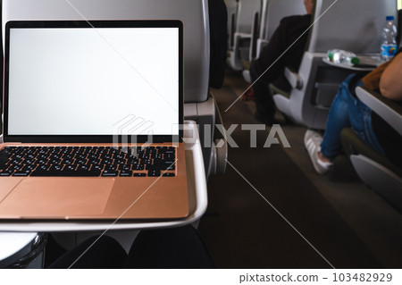 A laptop is set up on a table in a train car, providing a mobile office 103482929