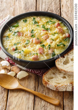 Soup kulesh with millet, potatoes and bacon in a black bowl closeup. Vertical 103483500