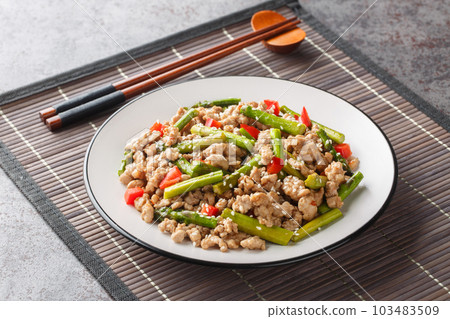 Delicious fried minced pork with asparagus, garlic, chili and sesame close-up in a plate. Horizontal Delicious fried minced pork with asparagus, garlic, chili and sesame close-up in a plate. Horizontal 103483509