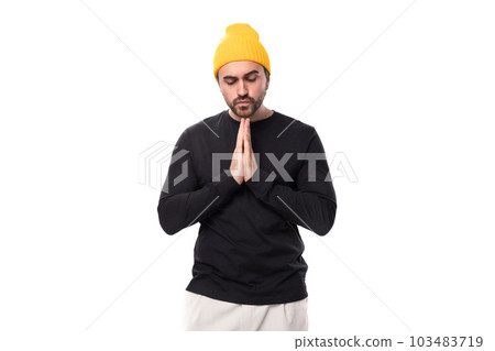 young brunette European brutal man in a black jacket prays and hopes 103483719