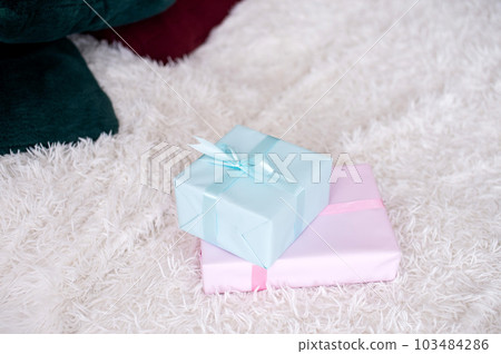 Gift boxes in pink and blue lie on a bed with a plaid 103484286
